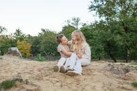 Familie broer en zus foto zittend en lachend op een heuvel